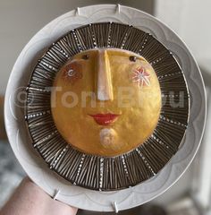 a person holding up a plate with a face on it