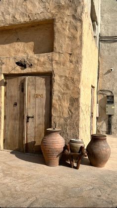 two large vases sitting next to each other on the side of a stone building