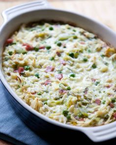 a casserole dish with broccoli, peas and ham in it on a blue cloth