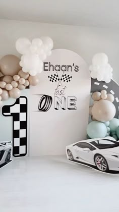 a room filled with balloons and cars in front of a sign that says, ehanan's first one