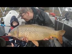 a man holding a large fish while sitting on a boat with a child in the background