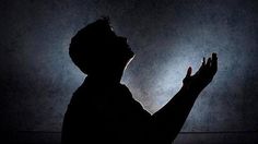 the silhouette of a man holding his hands up in the air, against a dark background