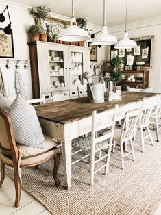 a dining room table with white chairs and lots of potted plants