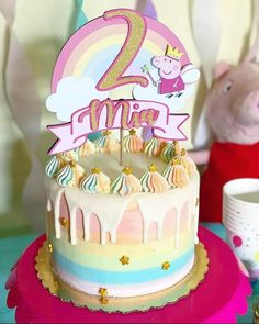 a birthday cake with the number two on it and a pink unicorn figurine next to it