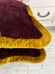 a close up of a pillow on a bed with a white dresser in the background