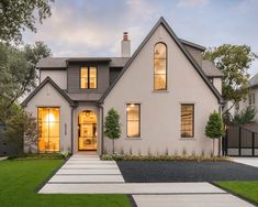 a white house with large windows in the front yard and grass on the side walk