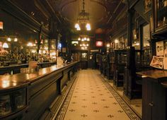 a dimly lit bar with lots of bottles on the shelves and lights hanging from the ceiling