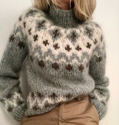 a blonde woman wearing a sweater and tan pants