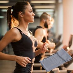 a woman running on a treadmill with other people in the background looking at her