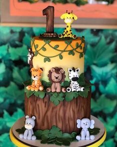 a three tiered cake decorated with animals and an animal number one on it's side