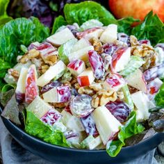 a salad with apples, walnuts and cranberry sauce in a black bowl