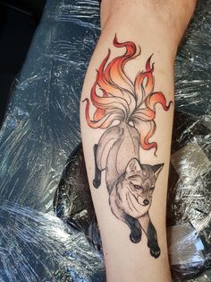 a tattoo on the leg of a person with a fox and flames around it's head