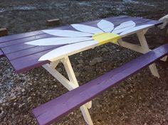 a purple picnic table with a white flower painted on it