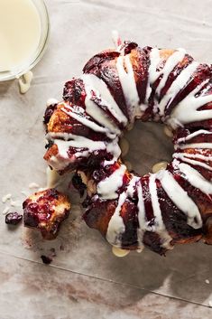 a bundt cake with white icing and cranberry sauce on it next to a glass of milk