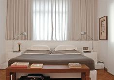 a bed sitting in the middle of a bedroom next to a table with books on it