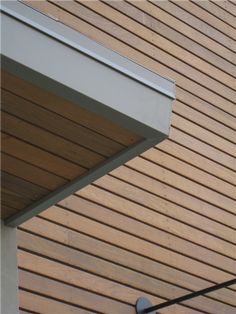 the corner of a wooden building with a white gutter on it's side