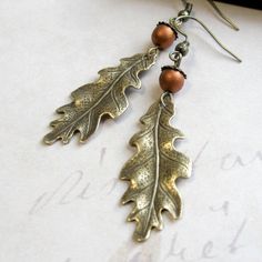 "Here is a lovely pair of oak leaf earrings, comprised of solid brass gold leaf charms, along with copper glass beads, which look like tiny acorns sitting atop the leaves. Earrings come on brass ear wires and are light weight and comfortable to wear. Adorable earrings, perfect for the nature lover! Made in the USA Oak keaf charms measure: 5/8\" x 1.5\" more from my collection here: http://www.etsy.com/shop/botanicalbird About: Botanical Bird is a collection of handcrafted fashion jewelry, both n Leaf Earrings Gold, Oak Leaf Earrings, Oak Leaf Necklace, Earrings Nature, Gold Bar Earrings, Gold Leaf Earrings, Cameo Jewelry, Fall Earrings, Leaf Jewelry