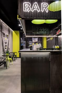 the interior of a bar with neon lights and black counter tops, yellow chairs, and artwork on the walls