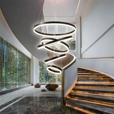 a spiral light fixture hanging from the side of a stair case in a modern building