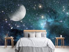 a bedroom with a bed, night sky and stars on the wall in front of it