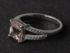 an engagement ring with a pink morganite surrounded by white diamonds on a black background