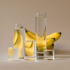 several glasses and bananas on a white surface