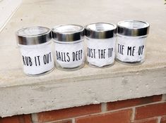 three jars with words painted on them are sitting on a ledge next to a brick wall