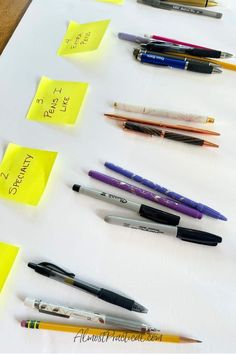 several pens are lined up on a table with sticky notes attached to the top of them