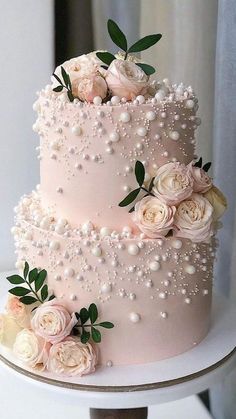 a three tiered cake with flowers and pearls on it