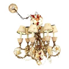 a chandelier with five lights and shells on the bottom, hanging from a chain