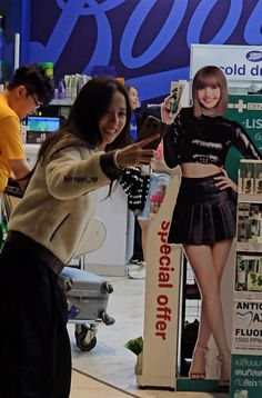 a woman is holding up a cell phone in front of a display