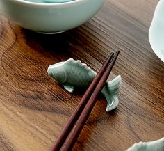 chopsticks and bowls on a wooden table with fish figurines next to them