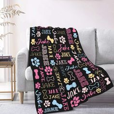 a black blanket with pink, yellow and blue dog paw prints is on a couch