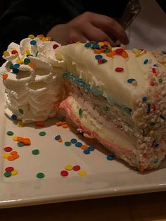 a large piece of cake with white frosting and sprinkles on a plate