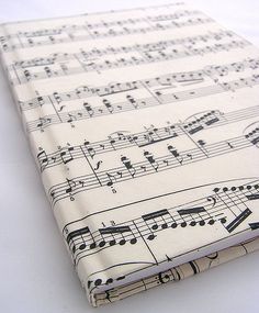 an old sheet music book with musical notations on it's cover, sitting on a white surface