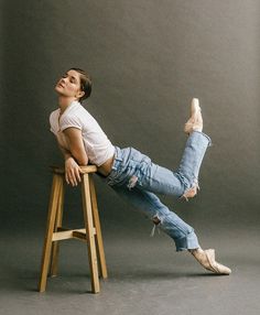 a man sitting on top of a wooden stool with his legs crossed and feet up in the air