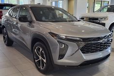 a silver chevrolet suv is on display in a showroom with other cars behind it