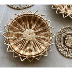 three woven baskets sitting on top of a floor next to each other, one with a circular design in the middle