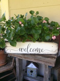 a potted plant sitting on top of a wooden stand next to a welcome sign