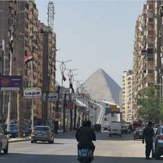 two motorcyclists are riding down the street in front of some tall buildings