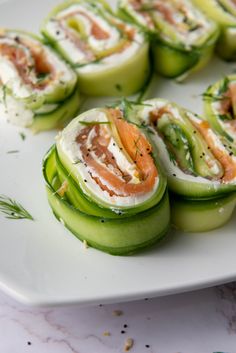 cucumbers with cream cheese and smoked salmon are arranged on a white platter