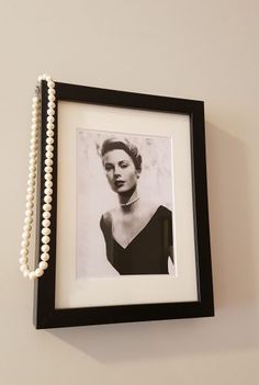 a black and white photo hanging on the wall with a beaded necklace attached to it