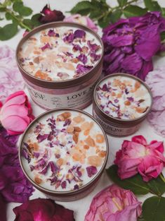 three jars filled with different types of food on top of purple and pink flowers next to each other