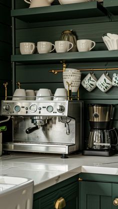 a coffee maker sitting on top of a kitchen counter next to green cabinets and cups