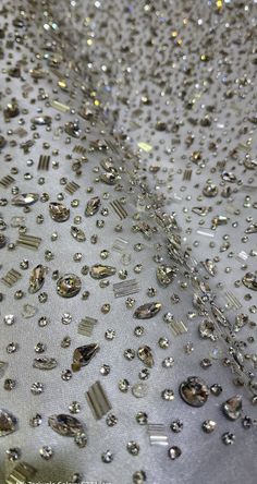 many different types of diamonds on a white cloth with silver sequins in the background