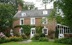 a large brick house surrounded by lush green grass and flowers on either side of it