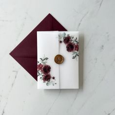 a white card with red flowers on it and a wax stamp sitting on top of it