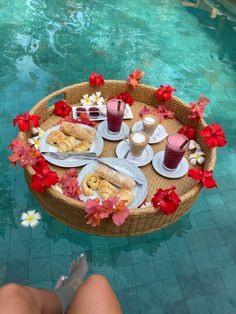 a table with food on it next to a swimming pool filled with water and flowers