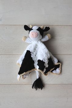 a black and white cow stuffed animal laying on top of a wooden floor next to a wall