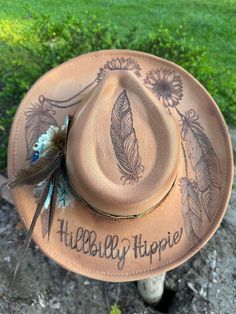 Hand burned sunflower and feather Hillbilly Hippie hat. This beauty is perfect for your next concert, dinner date or any special occasion. It's simply stunning. Hats are one size fits all with a drawstring to adjust sizing. Western Hats For Women Boho, Wood Burning Hats, Boho Hats For Women, Hat Burning Ideas, Burning Hats, Western Hat Styles, Burnt Hat, Western Hats For Women, Concert Hat